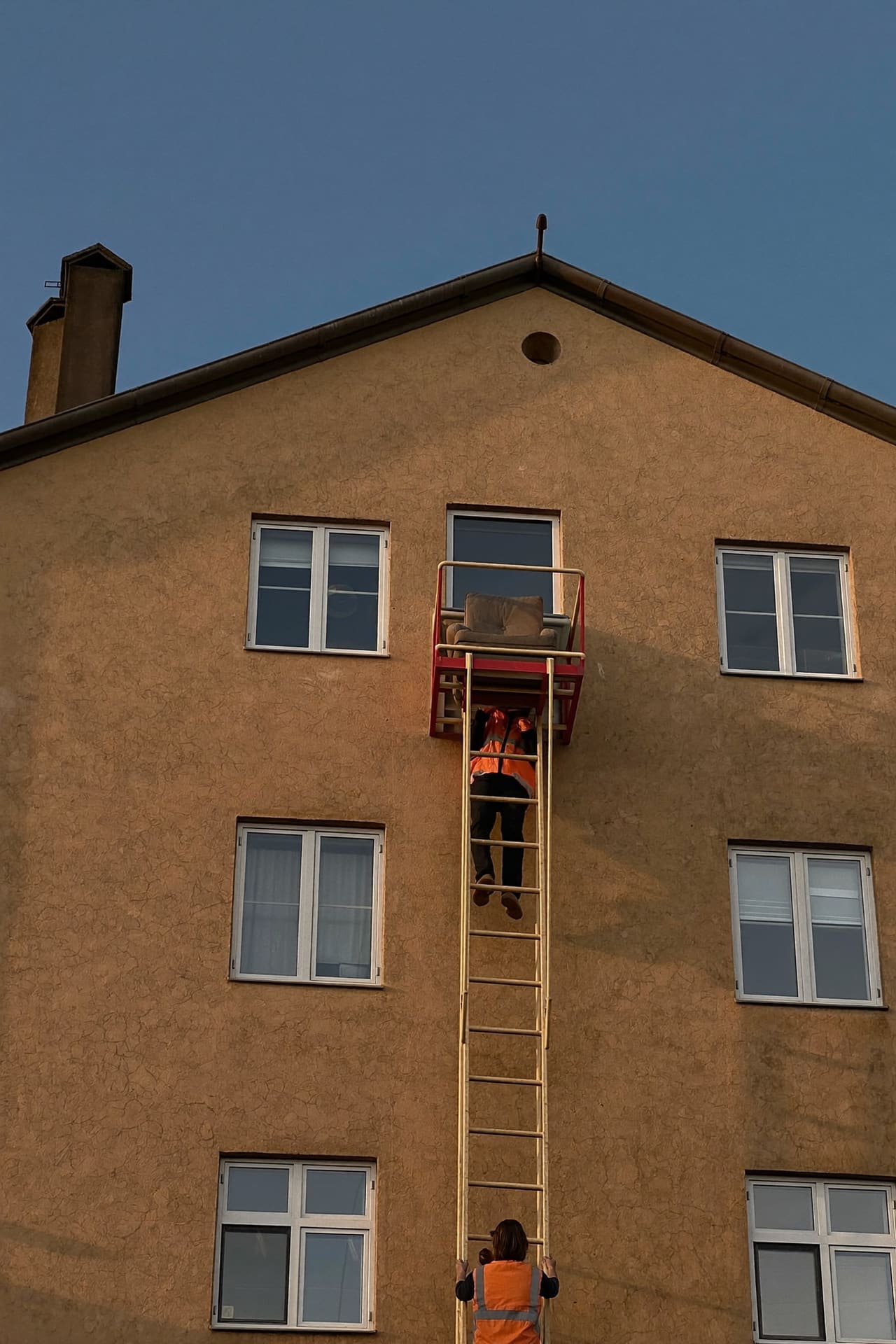 Außenmöbelaufzug an der Fassade eines Altbaus, ein Möbelpacker sichert die Plattform