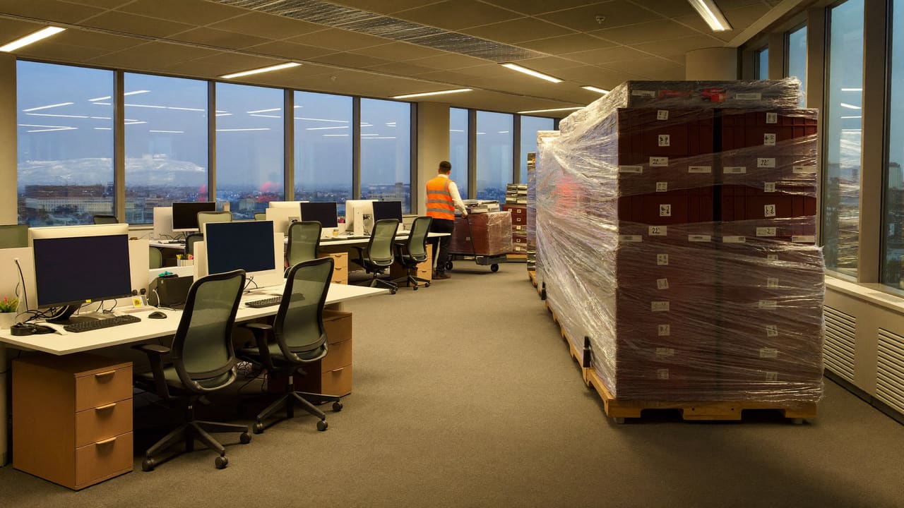 Büro im Umzug: Monitore in Schutzfolie, beschriftete Transportkisten